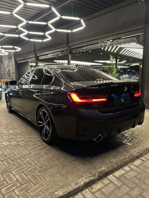 BMW 320i na cor preta, vista traseira em três quartos